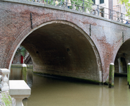 843701 Gezicht door een van de bogen van de Bakkerbrug over de Oudegracht te Utrecht, voor de restauratie van de brug.